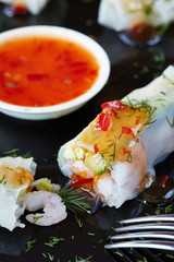 spring rolls with shrimps and sauce on dark plate