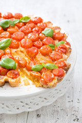 freshly baked tart with cherry tomatoes on white