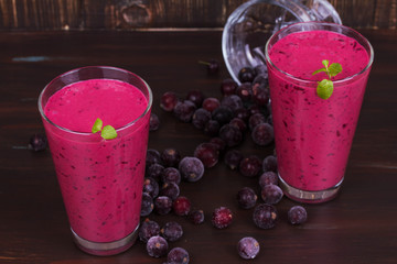 Frozen summer berries smoothie garnished with mint on dark wooden background