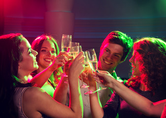 smiling friends with glasses of champagne in club