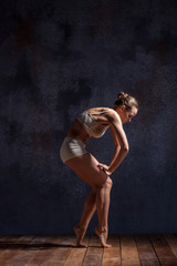 Young beautiful dancer in beige swimwear dancing on lilac background