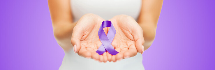 close up of hands holding purple awareness ribbon