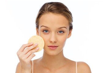 young woman cleaning face with exfoliating sponge