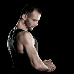 muscular man,  clasps hands in  fist, black background