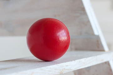 Red plastic ball on white shelf, light background