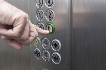 Forefinger pressing the zero floor button in the elevator