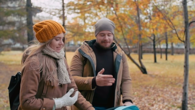 Young parents walking in the park with toddler watching cartoon on tablet in baby buggy