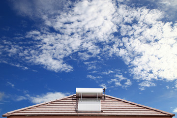 Solar panel for hot water system on roof on blue sky background.