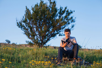 Naklejka na ściany i meble man sits on a hill with a book