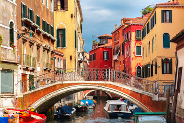 Fototapeta na wymiar Colorful lateral canal and bridge in Venice, Italy