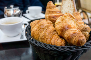 Breakfast with coffee and croissants in a basket on table