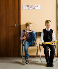Schoolboys are sitting beside the principal's office in school