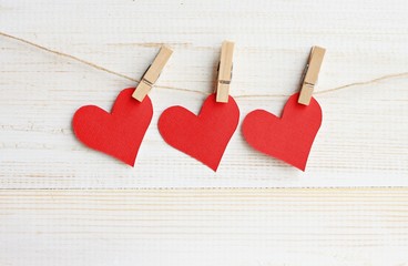 Red bright paper hearts pinned on twine rope, wooden wall empty background.