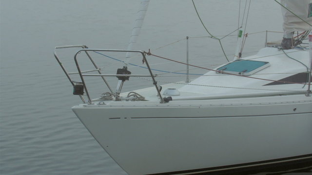 The white small speedboat on the port. It is docked on the small port foggy area