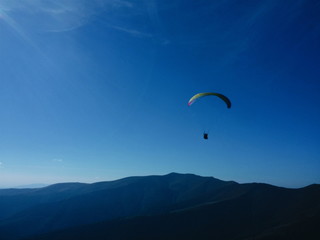 Man fly on paraglider above the mountains