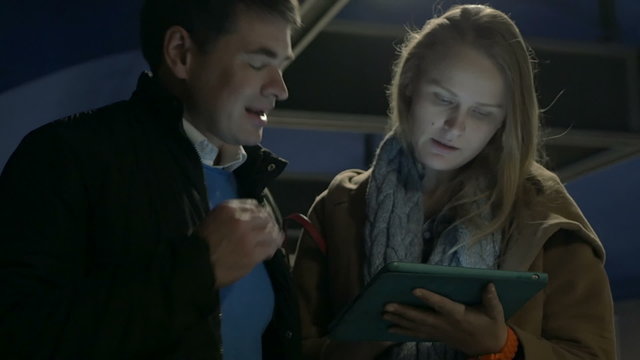Couple using tablet computer on flat escalator