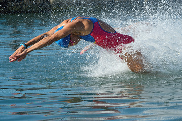 Triathlon participants running into the water for swim portion of race. Splash of water and...