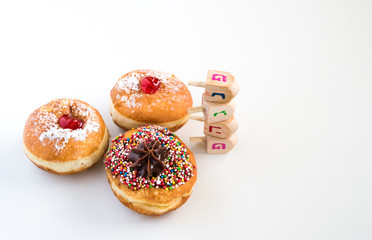 Close up of fresh donuts and wood dreidels  for Hanukkah Jewish Holiday.