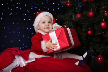 Baby in a Christmas santa costume with gift