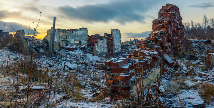 Apocalyptic landscape.The remains of destroyed houses covered with snow at sunset