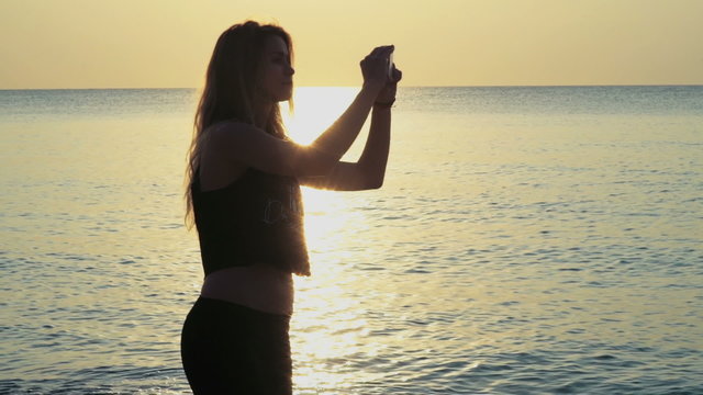 young sportive joyful female makes selfie on the beach slow motion