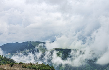 Green mountain hills among clouds and lonely house