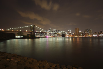 Fototapeta premium Wide angle view of the Brooklyn Bridge and Manhattan skyline as seen from across the East River at dusk.