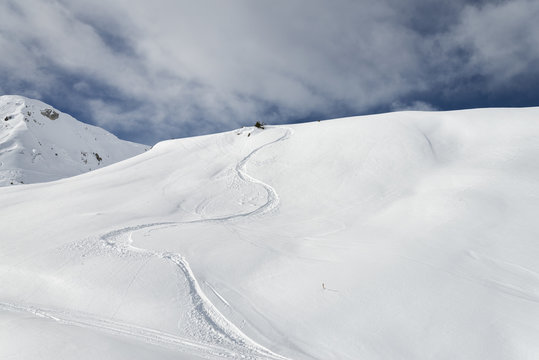 Winding snowboard trail among virgin snow mountains