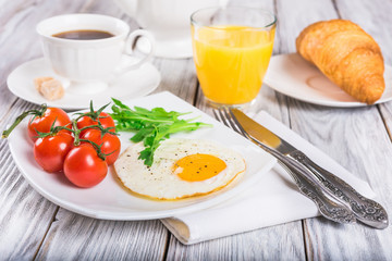 Breakfast with cup of coffee, egg, croissant and orange juice on wooden table