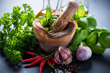 Fresh herbs and spices in wooden mortar