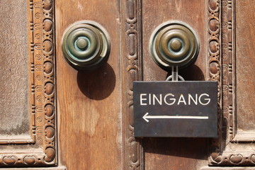 Naklejka premium Historical wooden door with a direction sign 