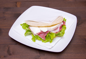 Flatbread with ham and mozzarella on wooden table