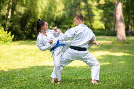 Young woman and man practicing martial arts outdoors