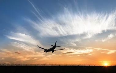 Fotobehang Plane is landing at the sunset © roman_baiadin