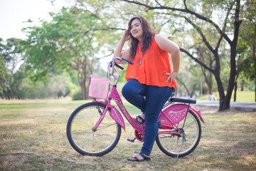 Naklejka premium Happy fatty woman posing with bicycle