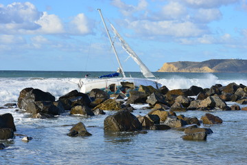 Fototapeta premium A Yacht being ship wrecked on the rocks on the beach at San Diego, California 