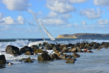 A Yacht being ship wrecked on the rocks on the beach at San Diego, California
