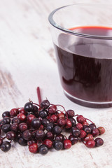 Bunch of fresh elderberry with juice on old wooden background, healthy nutrition