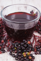 Bunch of fresh elderberry with juice on old wooden background, healthy nutrition