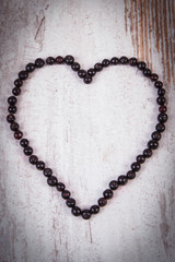 Heart of fresh elderberry on old wooden background, symbol of love