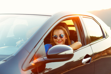 Smiling woman driving a car at sunset