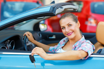 Young pretty woman sitting in a convertible car with the keys in