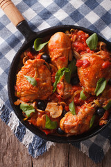 Cacciatori Chicken with black olives close-up in a pan. vertical top view
