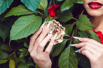 Beautiful girl with a manicure on a background of leaves