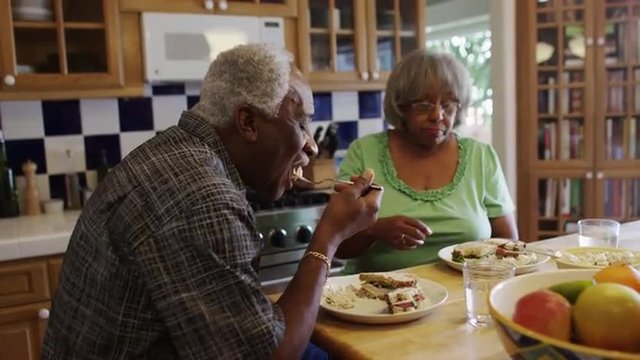 Mature African couple eating lunch together in kitchen