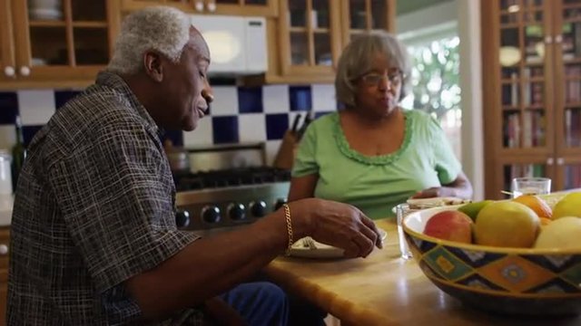 Mature black couple eating lunch together in kitchen