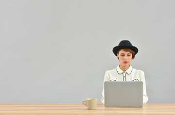 Woman with black hat working on laptop, isolated