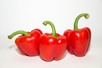 Three ripe red  peppers on over white