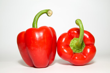 Two ripe red  peppers on over white
