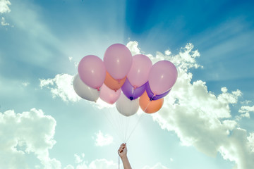 Fototapeta na wymiar hand holding colorful balloons on blue sky background 